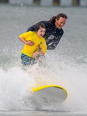 children in the water on surf boards with surf instructors